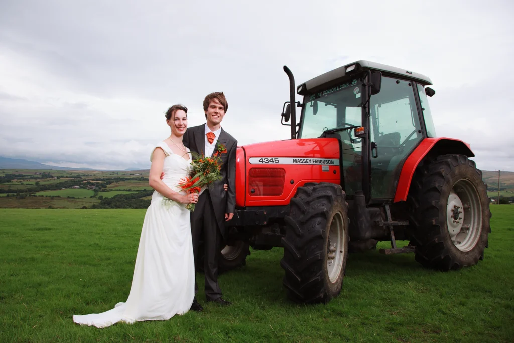 farm wedding photo of bride and groom stood next to their tractor