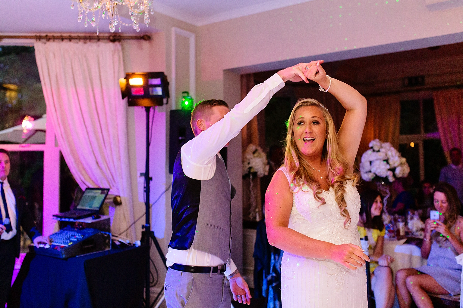 wedding photo of bride and grooms first dance. groom is twirling the bride.